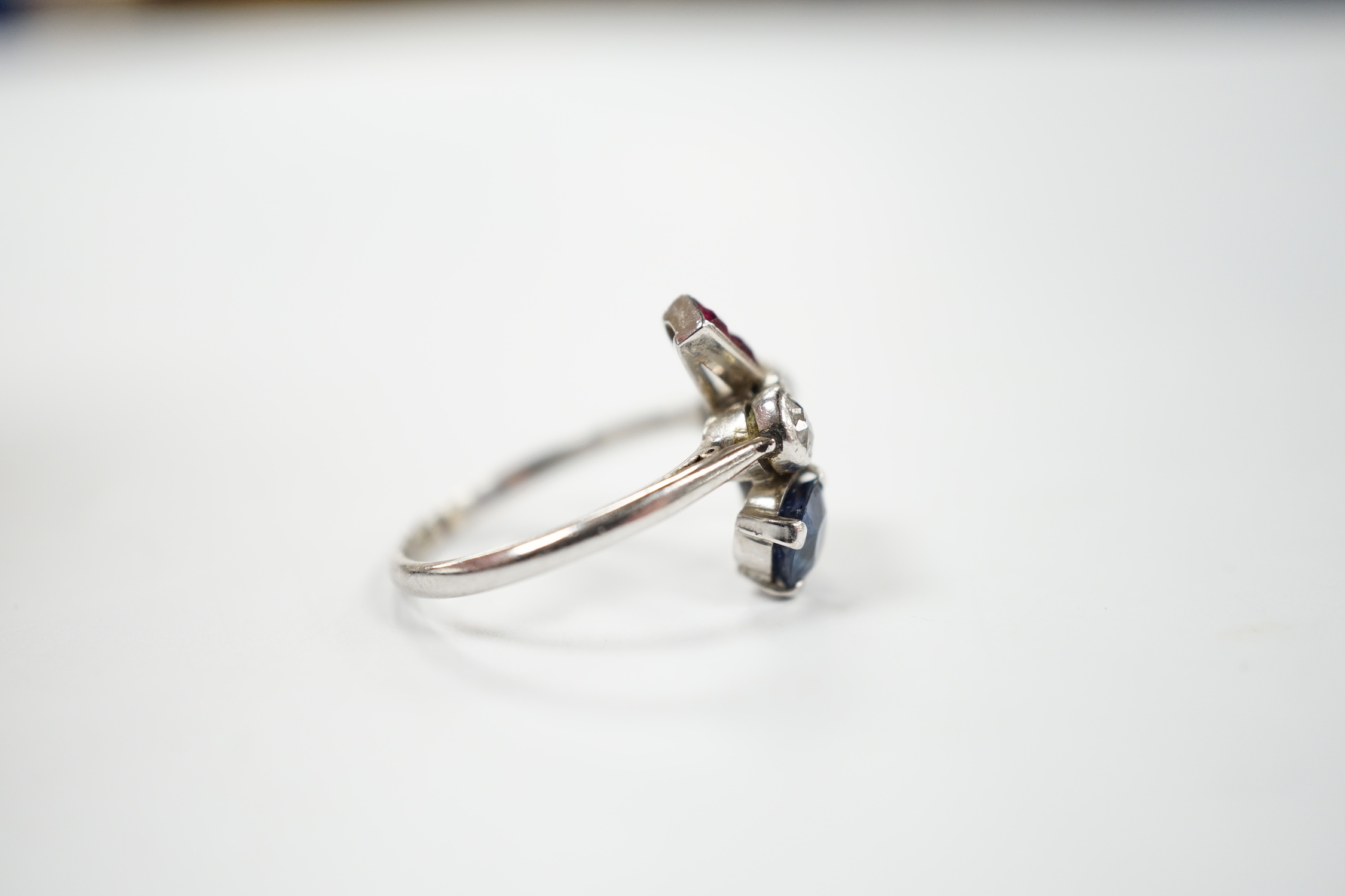 An unusual 1920's/1930's platinum, ruby, sapphire and diamond cluster set dress ring, of free form, the stones in a millegrain, claw or collet settings, size I, gross weight 3.7 grams.